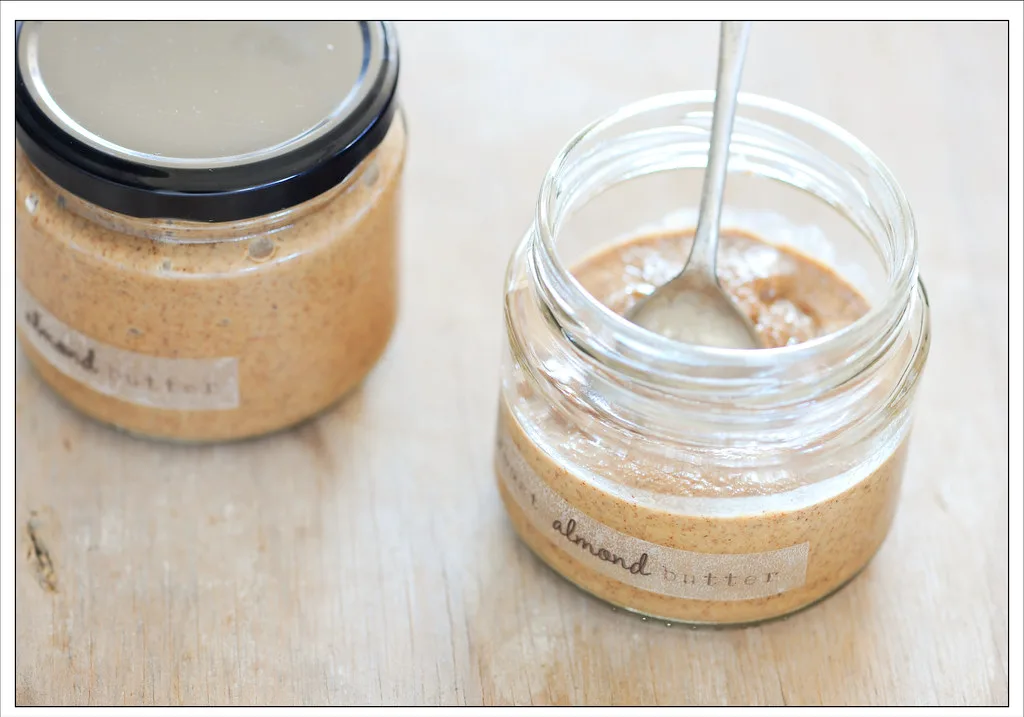 Open jar of natural almond butter with a spoon