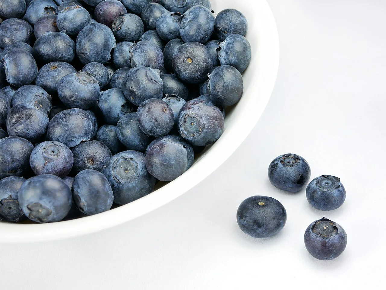 A white dish piled with fresh ripe blueberries