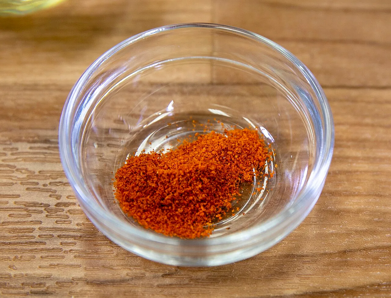 Bright orange-red cayenne pepper powder in a small glass bowl