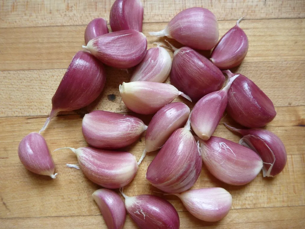 Peeled garlic cloves on a wooden cutting board