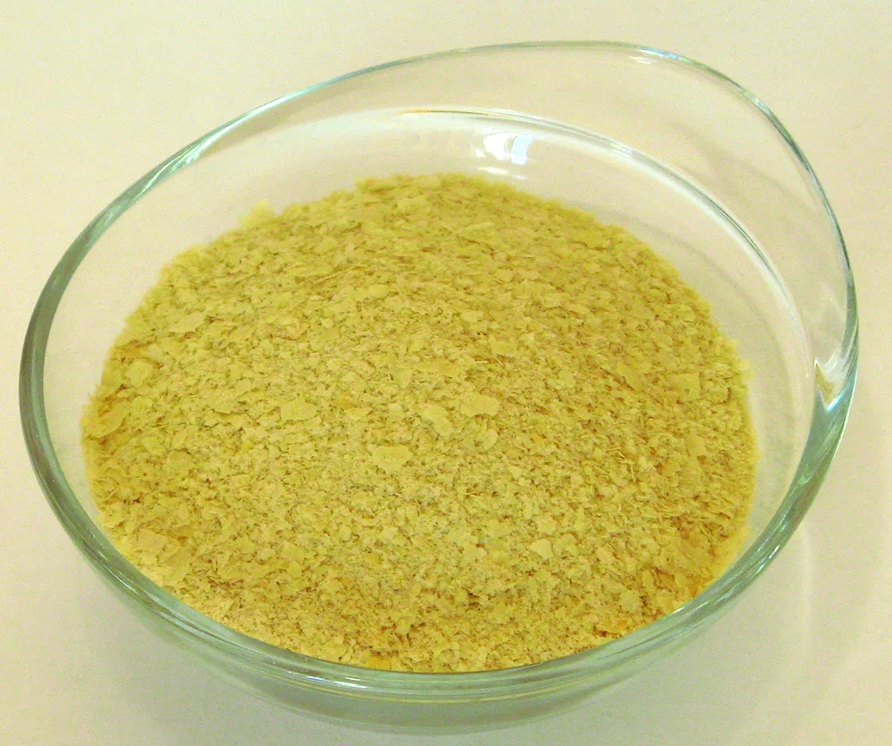 Golden nutritional yeast flakes in a clear glass bowl