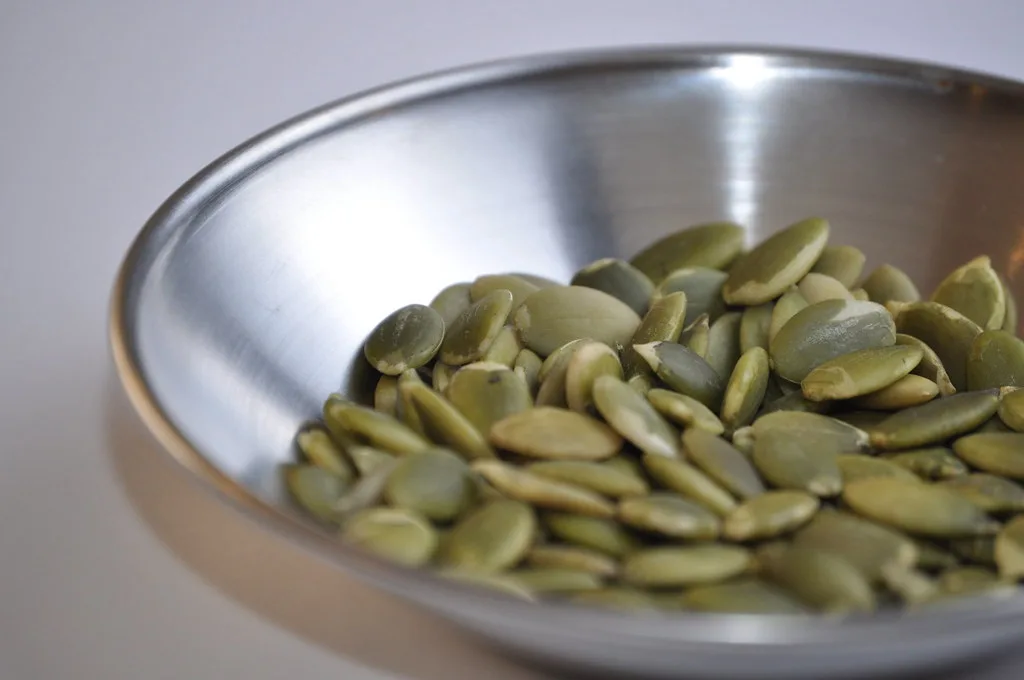 Green pepita pumpkin seeds in a silver bowl
