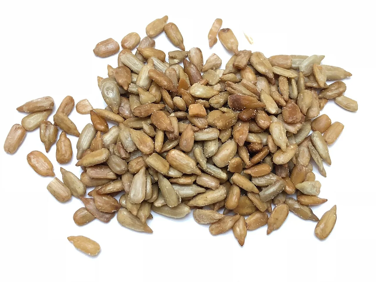 Hulled sunflower seed kernels in a loose pile on a white background